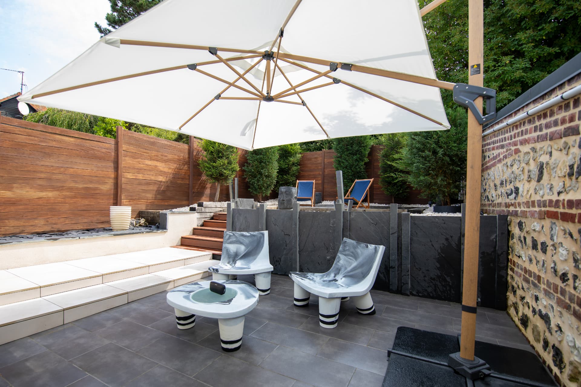 Terrasse privative de L'Échappée avec parasol et fauteuils design