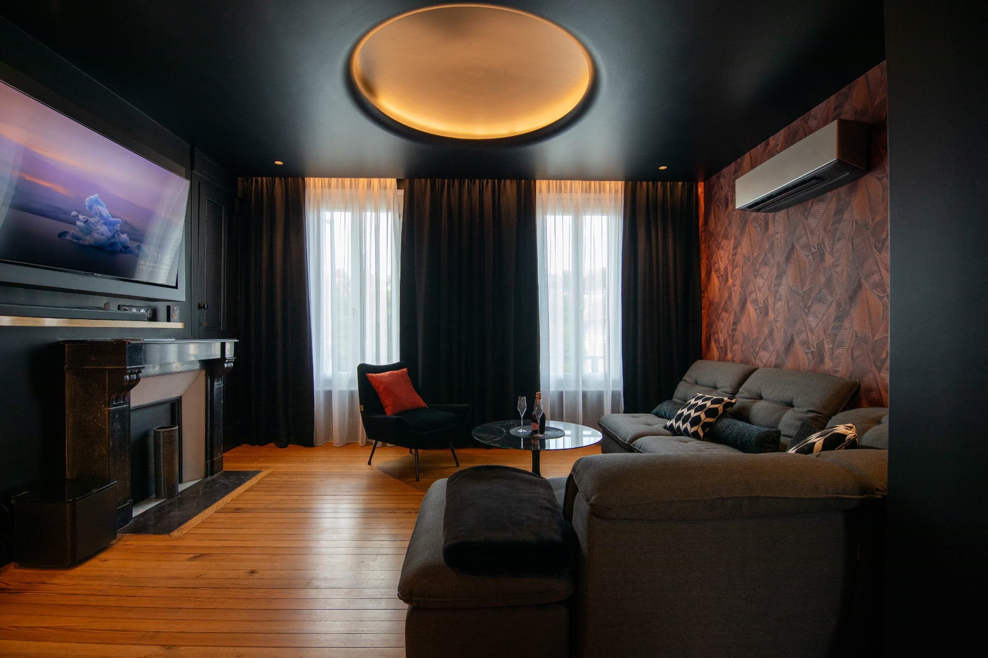 Salon de L'Échappée avec cheminée en marbre noir, parquet et grandes fenêtres