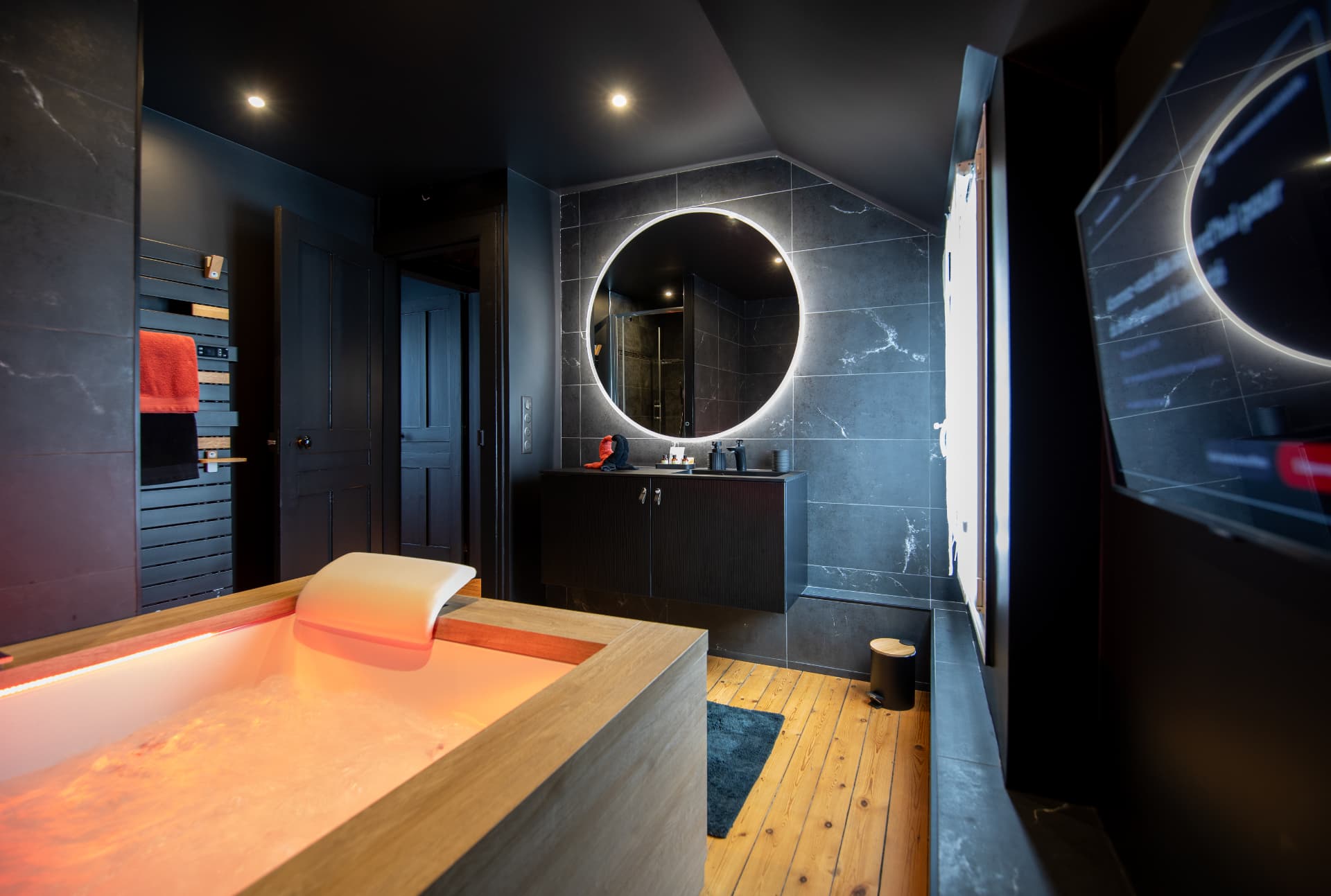 Salle de bain de L'Échappée : baignoire balnéo, vasque et miroir rétroéclairé